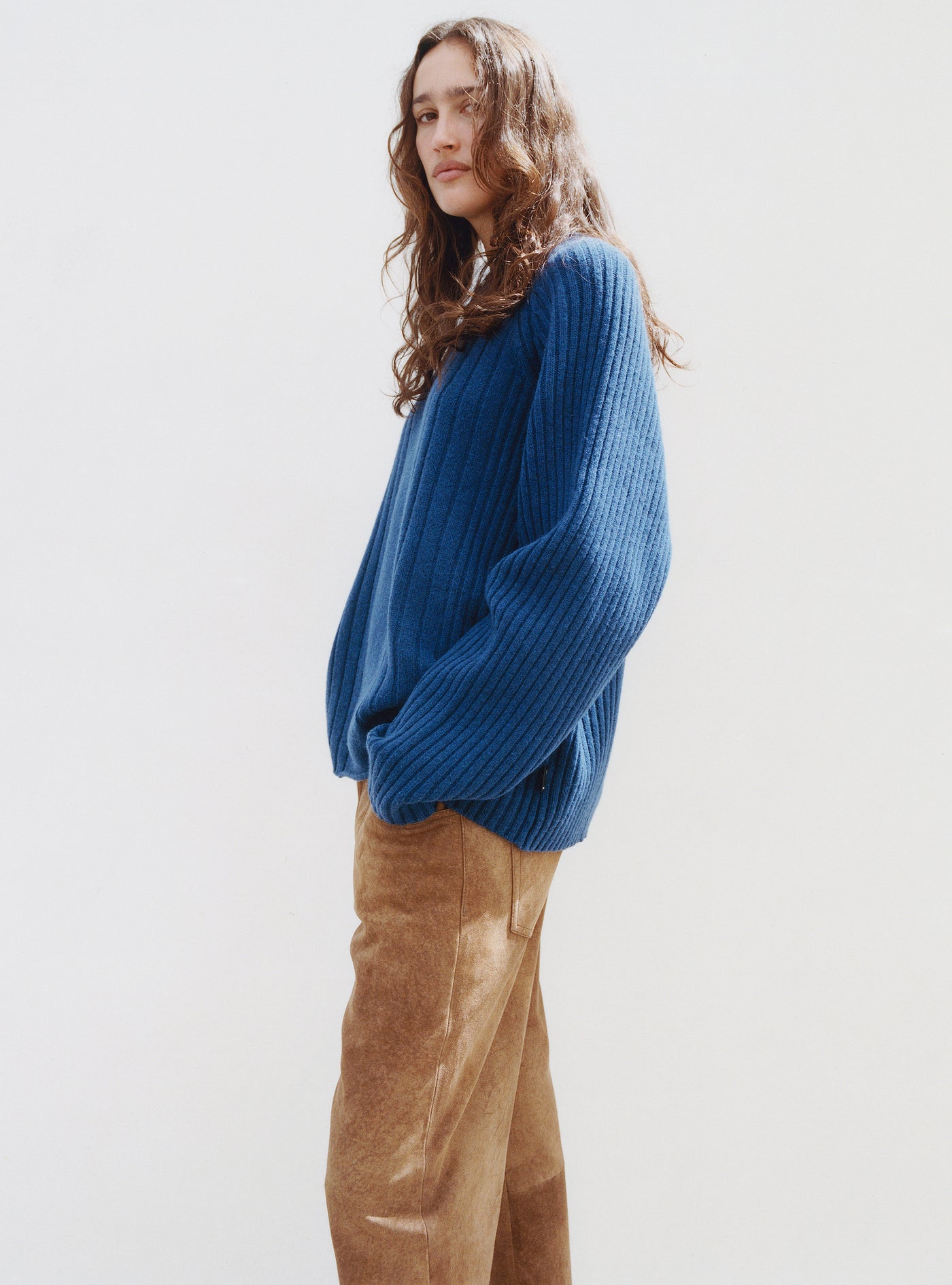 01 collection fall26 Personne portant un pull en maille bleue Stüssy et un pantalon en velours côtelé