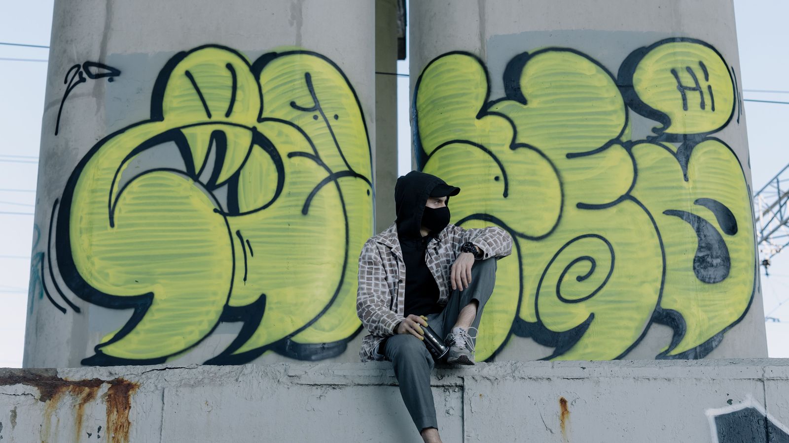 Personne assise devant un graffiti jaune de grande taille