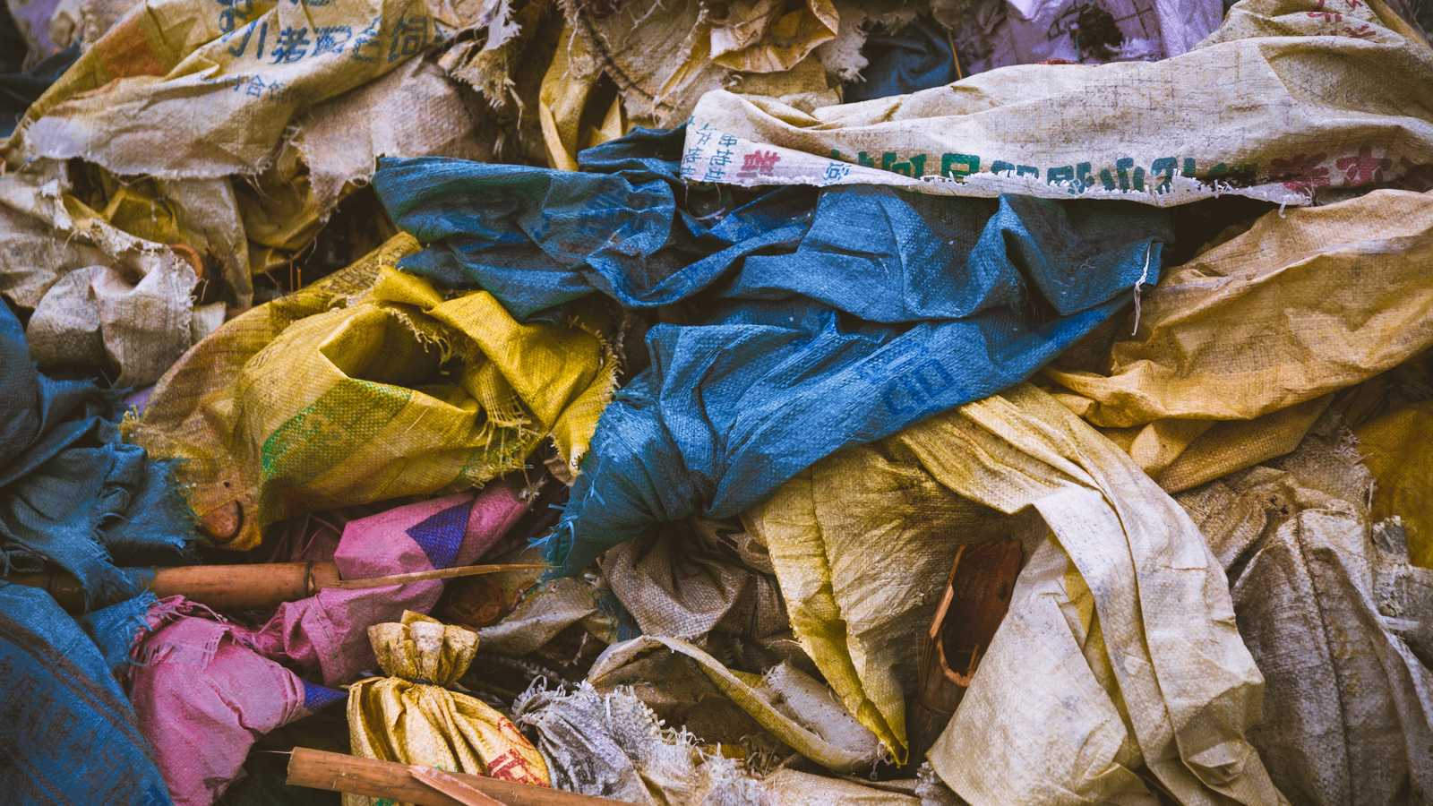 01 inv Sacs de déchets textiles éventrés laissant apparaître des vêtements