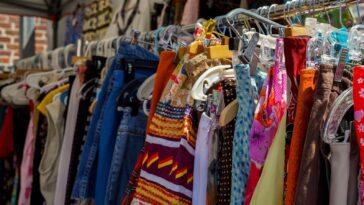 Portants remplis de vêtements colorés dans une friperie