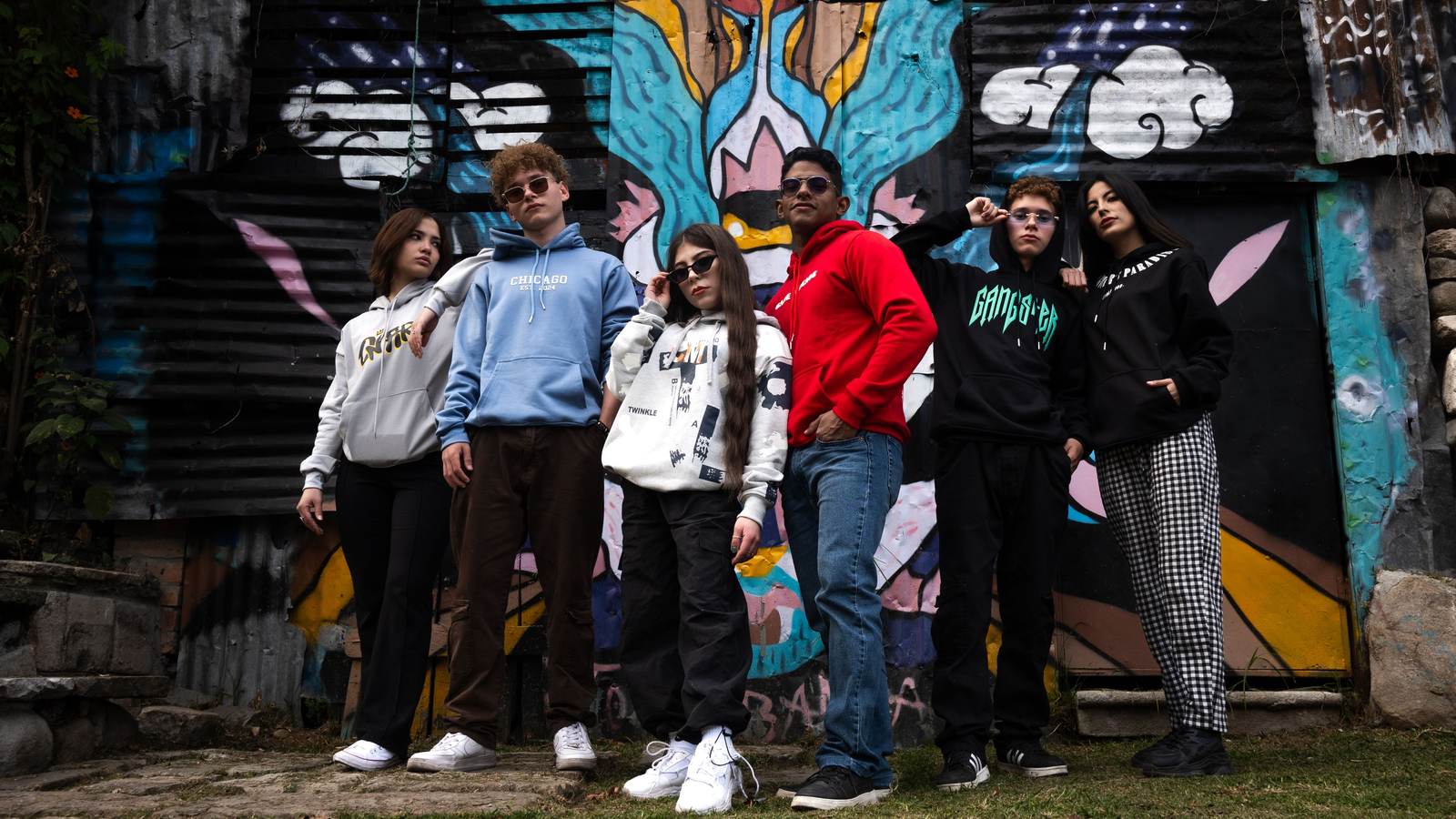 03 hoo Groupe de jeunes en hoodies devant un mur couvert de graffitis