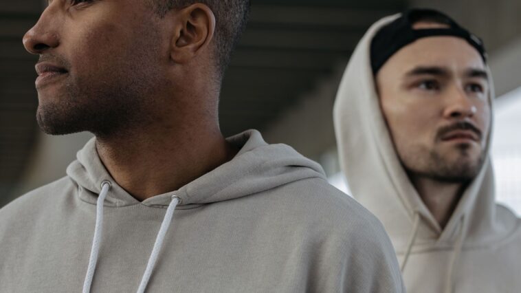 Deux hommes en hoodies beiges, l'un capuche relevée