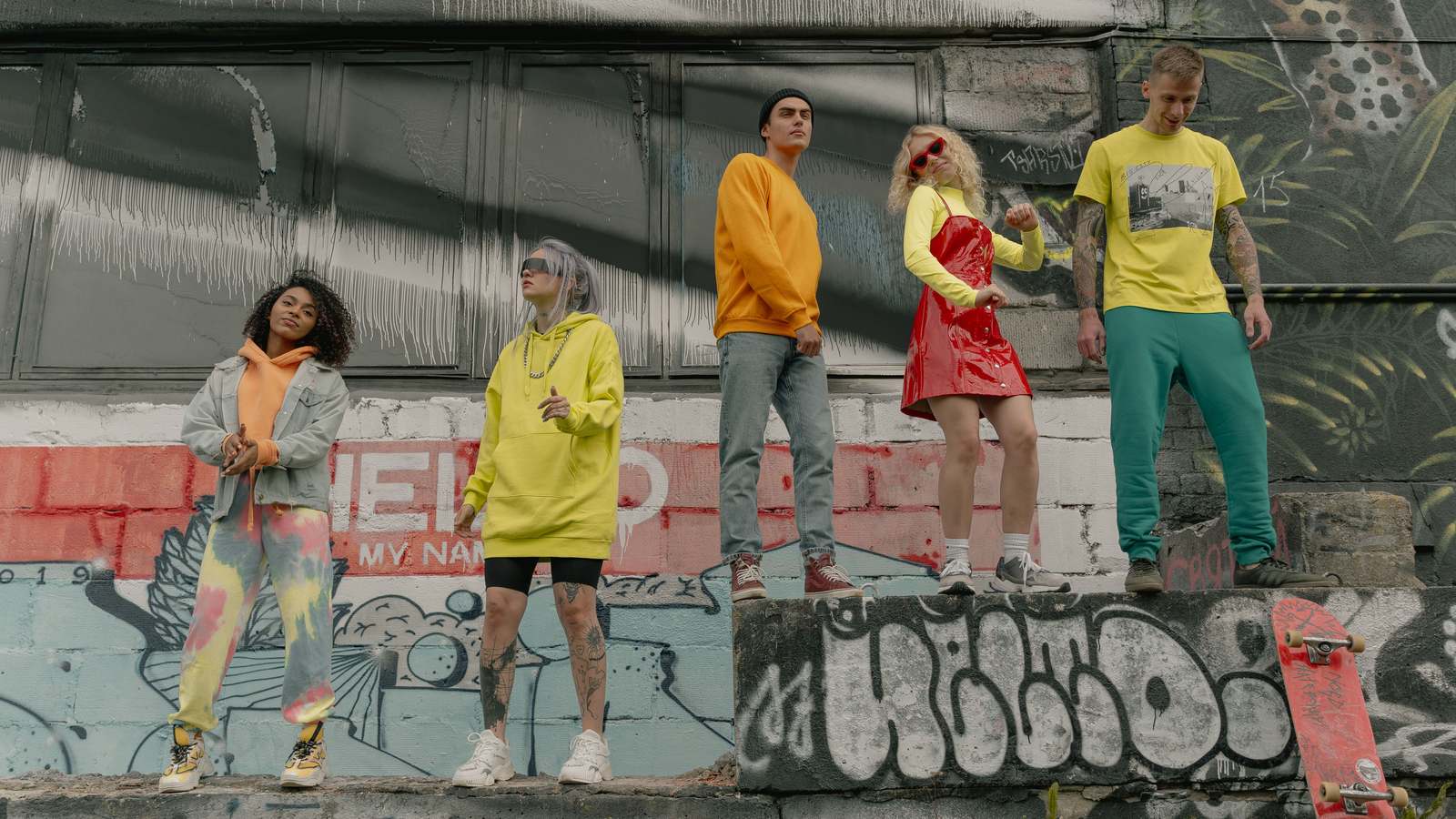05 cul Cinq personnes en streetwear debout sur un muret couvert de graffitis