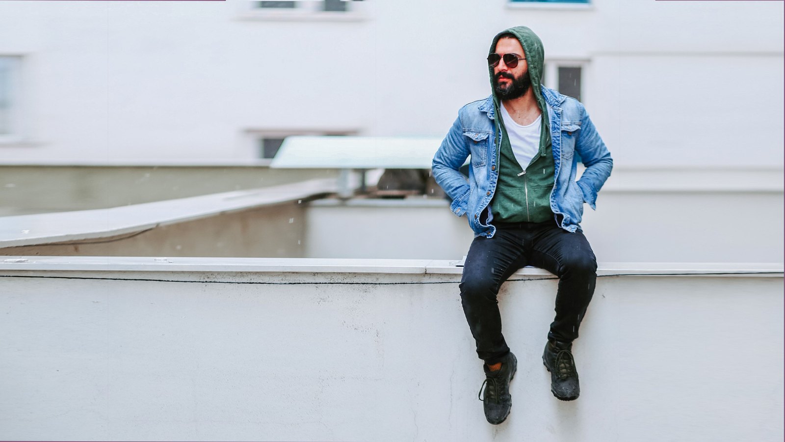 06 lay Homme assis portant une veste en jean sur un hoodie vert