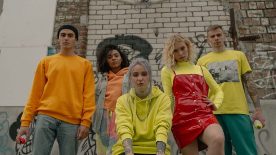 Groupe de jeunes en tenues streetwear assis contre un mur de briques