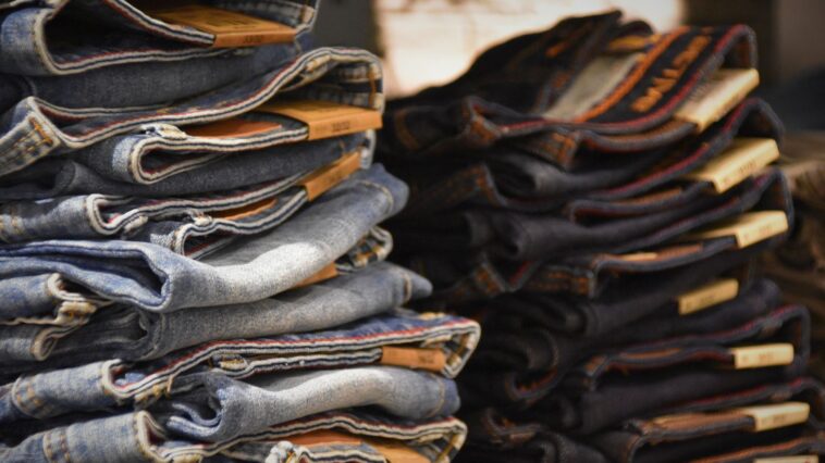 Piles de jeans de délavages différents empilées sur un étal de marché