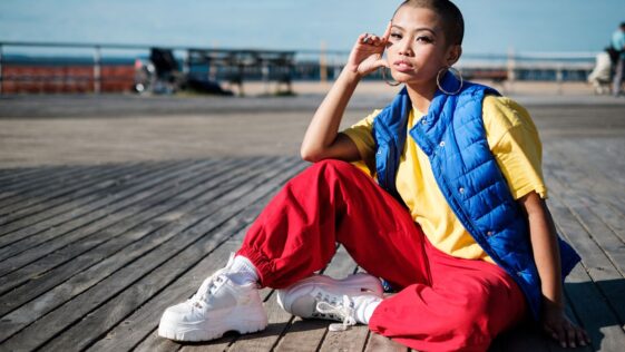 Personne assise en doudoune bleue, haut jaune et pantalon rouge