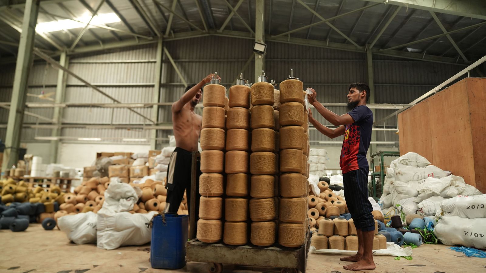 10 inv Ouvrier empilant des bobines de fil dans un entrepôt textile