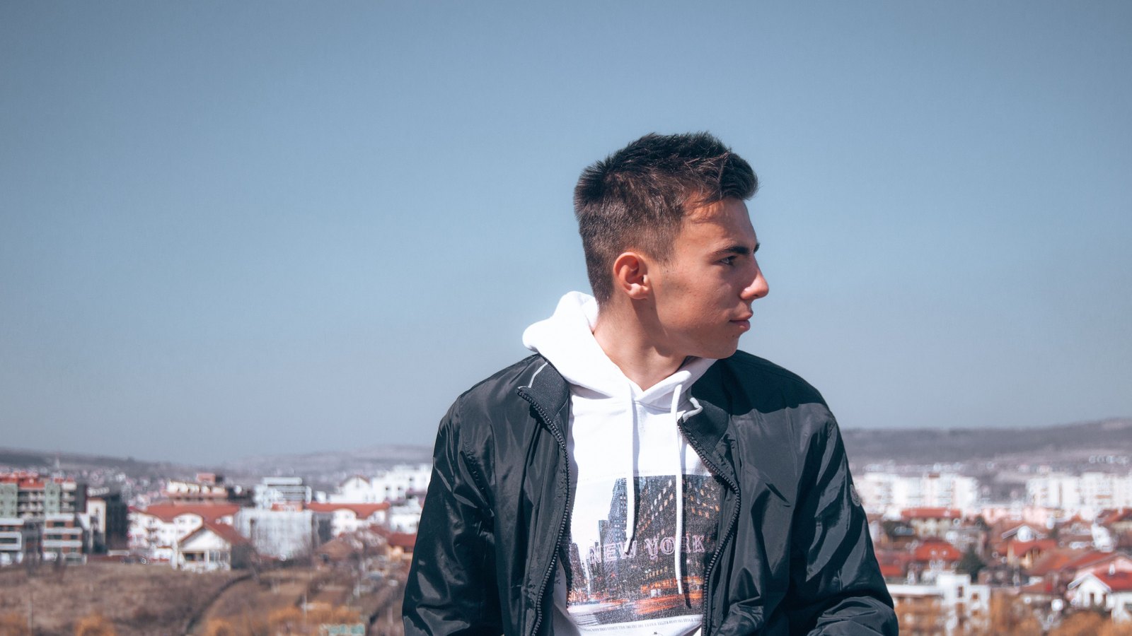10 lay Jeune homme en veste noire ouverte sur un hoodie blanc